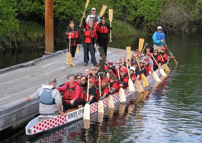River Spirit paddlers seated in their dragon boat at the dock